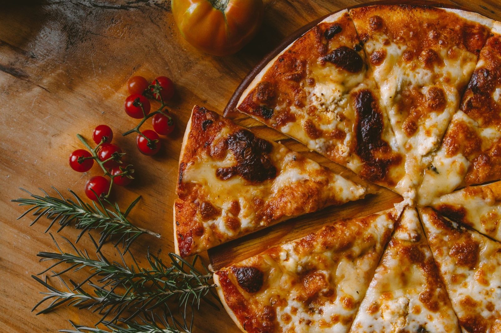 Sliced cheese pizza with fresh tomatoes and rosemary